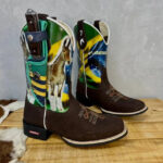 BotaFaca Muladeiros do Brasil
                                    - Couro Cano Nobuck Cru com Estampa | Couro Gáspea Nobuck Chocolate Estilizado em Tilápia | Florão com Cruz e Bainha Brasileira